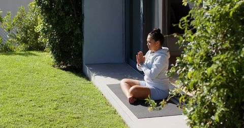 Woman practicing mindfulness outdoors on yoga mat