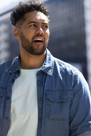 Sunlit african american man speaking outdoors wearing denim shirt urban crewneck portrait