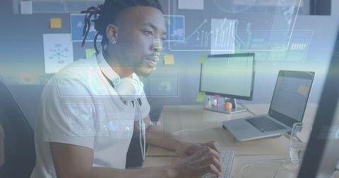 Data analyst typing at dual-monitor desk while interacting with holographic analytics