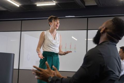 Mid adult woman presenting charts in modern conference room