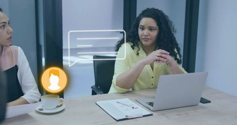 Woman sitting at meeting table with laptop and chat ui overlay collaborating in office