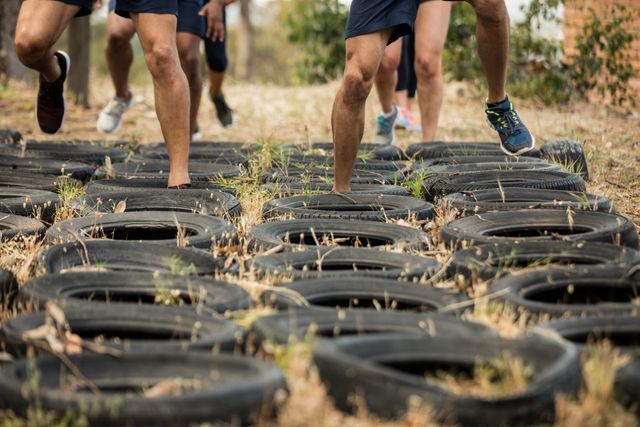 Low section of people receiving tire obstacle course training in boot camp