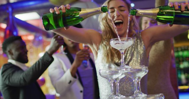 Image of happy caucasian woman pouring a champagne fountain into glasses at nightclub. Fun, drinking, going out and party concept.