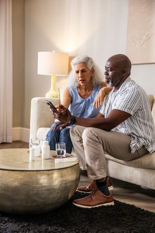 Senior couple discussing medication using smartphone at home