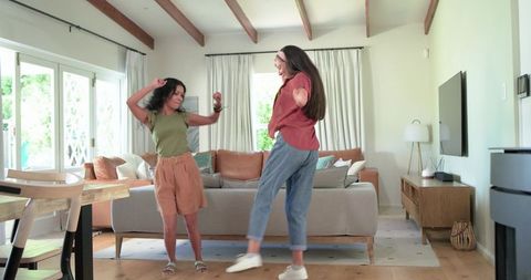 Indian and african women dancing in sunlit living room sharing friendship and joy