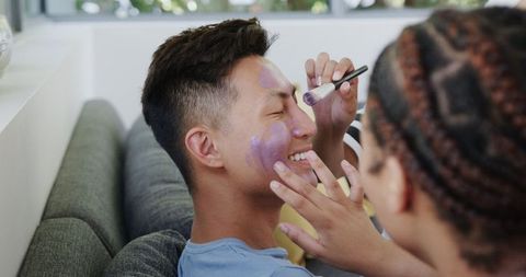 Asian Man and Biracial Woman Laughing While Applying Face Masks