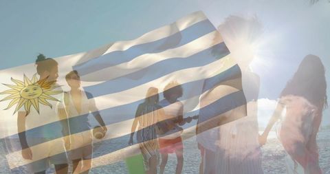 Walking friends on sunlit beach with uruguay flag overlay at golden hour