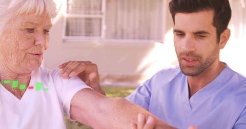 Nurse assisting senior woman with arm exercise outdoors at home