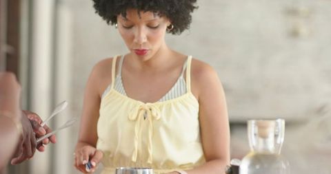 African american woman stirring and measuring ingredients for baking on kitchen counter