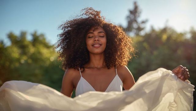 Sunlit woman in flowing white dress enjoying summer breeze in garden at golden hour