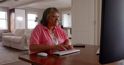 Senior woman using computer for remote work in modern home