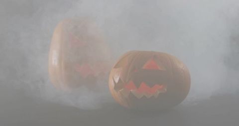 Flickering jack-o'-lantern glowing through fog on dark matte tabletop for halloween decor