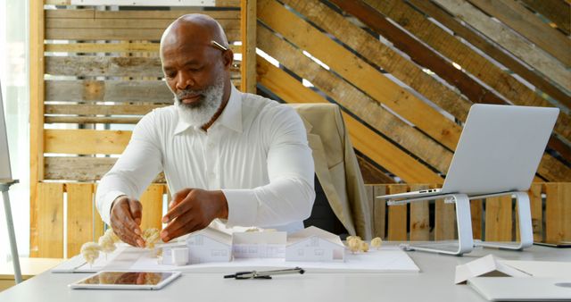 African American architect reviews model plans at his office. His workspace reflects a creative and professional environment.