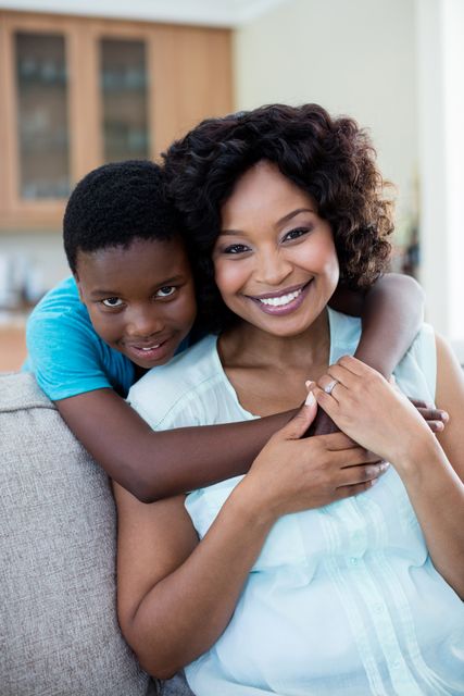 Mother and son embracing in living room, showcasing family love and bonding. Ideal for use in family-oriented advertisements, parenting blogs, and articles about home life and relationships.
