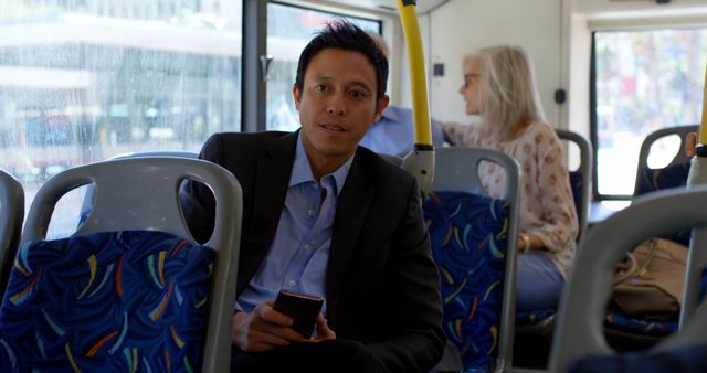 Biracial man sitting in city bus using smartphone. Communication, transport, city living and lifestyle, unaltered.
