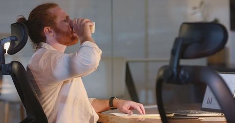 Dedicated professional working overtime at office desk with coffee