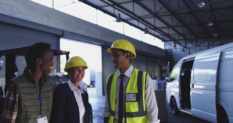 Warehouse team conducting safety briefing in distribution bay with hi-vis and helmets