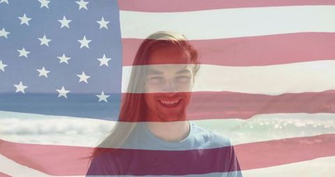 Smiling man standing on sunny beach with american flag overlay double exposure patriotic