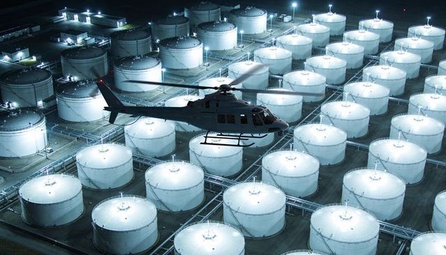 Night Helicopter Overflight Above Illuminated Fuel Storage Tanks and Piping Terminal
