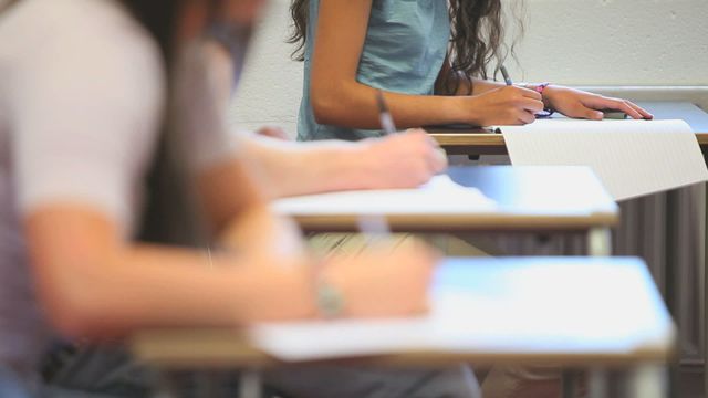 Students are seated in rows at desks, writing notes attentively, indicating an academic setting. This video can be used to represent themes of education, student life, active engagement in learning, and classroom environments in various educational contexts such as schools and tutoring centers.