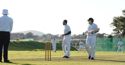 Male Cricket Teammates Competing on Sunny Field