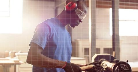 Woodworker shaping wooden cylinder on lathe wearing safety goggles and ear protection in workshop