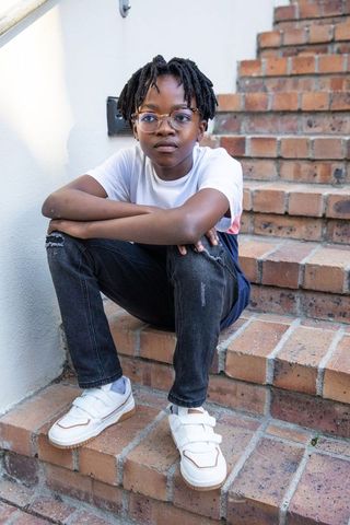 Teen with Glasses Sitting on Brick Steps in Urban Style