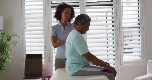 Biracial female physiotherapist helping senior man massaging his back - Download Free Stock Photos Pikwizard.com
