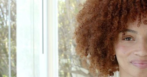 African american woman smiling by window natural light portrait curly hair hoop earring