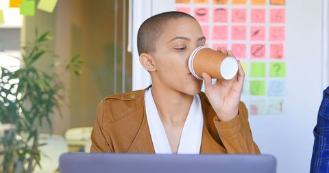 Young Professional Sipping Coffee at Modern Office Desk