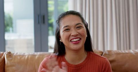 Cheerful Woman in Cozy Living Room Waving at Home