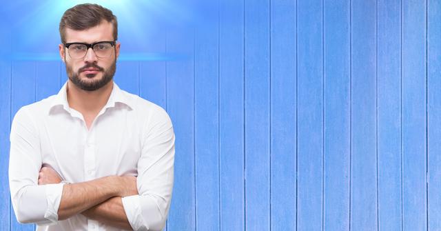 Young professional man standing confidently with arms crossed, wearing glasses and white shirt, against vertical blue wooden plank background. Ideal for business, corporate, professional themes, or career growth visuals. Useful for websites, advertisements, corporate presentations, social media banners.