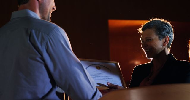 This image depicts a formal award ceremony where an employee is presented with a certificate by a professional. Ideal for illustrating professional recognition, corporate events, employee achievement, and workplace success stories. Suitable for use in corporate brochures, HR presentations, business websites, and motivational content.