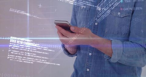 Man scrolling smartphone in denim shirt with futuristic binary data and holographic interface