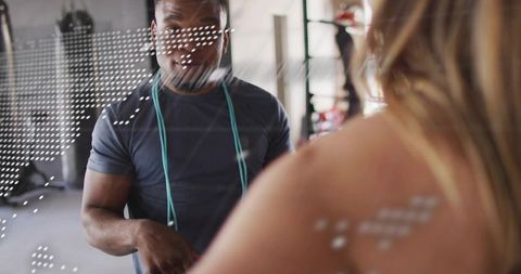 Personal trainer coaching client in gym mirror with jump rope in modern industrial studio