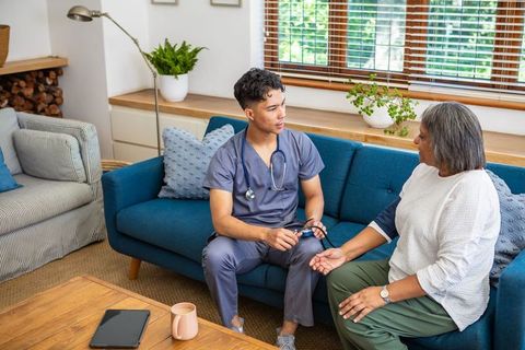 Home Healthcare Nurse Assisting Senior Woman on Sofa