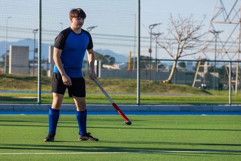 Field Hockey Player Standing on Turf Pitch Holding Stick