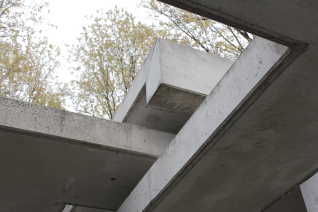 Photograph showcases an abstract geometric architectural concrete structure featuring clean lines and angles. Ideal for illustrating modern architecture concepts, urban design, or minimalist aesthetic. Can be used in publications, articles on contemporary architecture, or for backgrounds in design projects due to its clean and neutral tones.