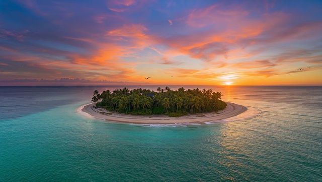 Sunset glowing palm-ringed tropical islet surrounded by turquoise lagoon and coral reef