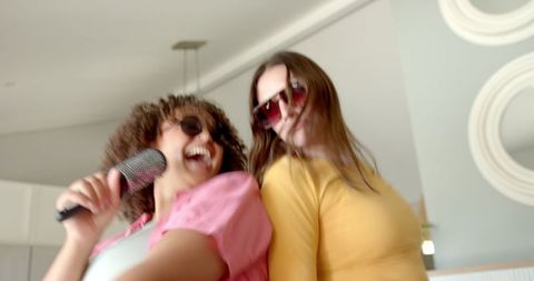 Joyful Female Friends Singing with Microphone at Home