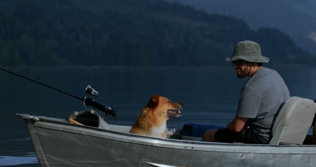 A man enjoys quiet fishing on a lake with his dog in a small boat. This tranquil scene showcases outdoor leisure, adventure, and companionship between the man and his pet. Perfect for use in content related to fishing, outdoor activities, summer vacations, pet companionship, and nature retreats.