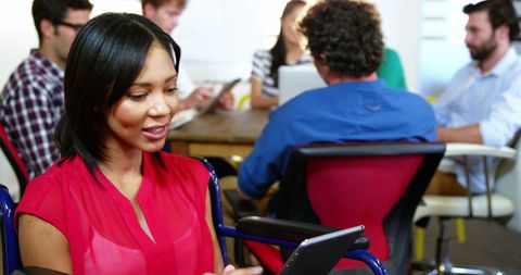 Casual businesswoman using tablet in diverse office setting