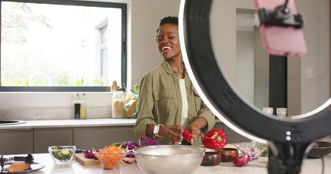 African American content creator recording cooking tutorial with ring light in kitchen