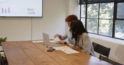 Diverse Colleagues Discussing Charts in Office Meeting
