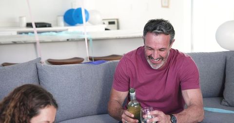 Cheerful Man Pouring Wine at Casual Home Birthday Celebration
