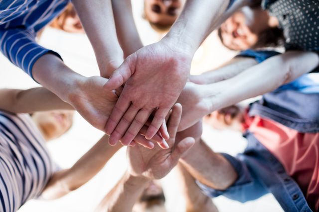 This image depicts a group of business professionals stacking their hands together, symbolizing teamwork, unity, and collaboration. Ideal for use in corporate presentations, team-building workshops, motivational posters, and business websites to convey the importance of cooperation and collective effort.