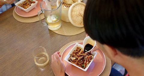 Eating Together at Rustic Table with Soy Sauce and Noodles