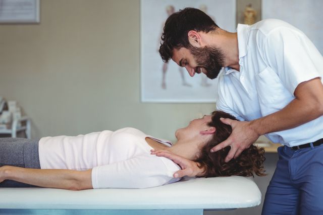 Physiotherapist giving neck massage to a woman in clinic
