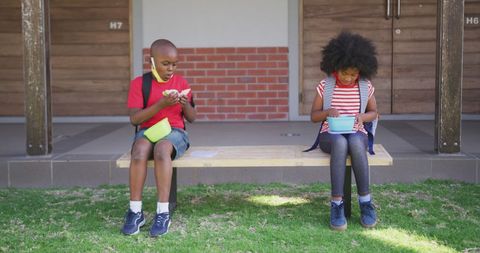 Children Social Distancing with Face Masks While Having Breakfast Outdoors