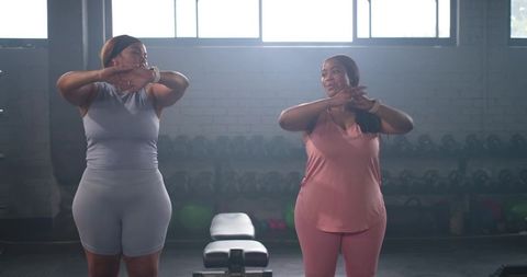 Diverse mid-adult women stretching in gym wearing fitted athleisure with wrist trackers